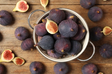 Whole and cut tasty fresh figs on wooden table, flat lay