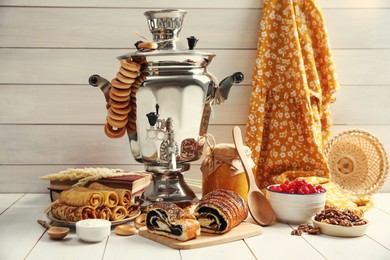 Photo of Traditional Russian samovar and treats on white wooden table