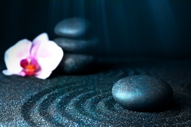 Spa stones and orchid flower on black sand with beautiful pattern. Zen concept