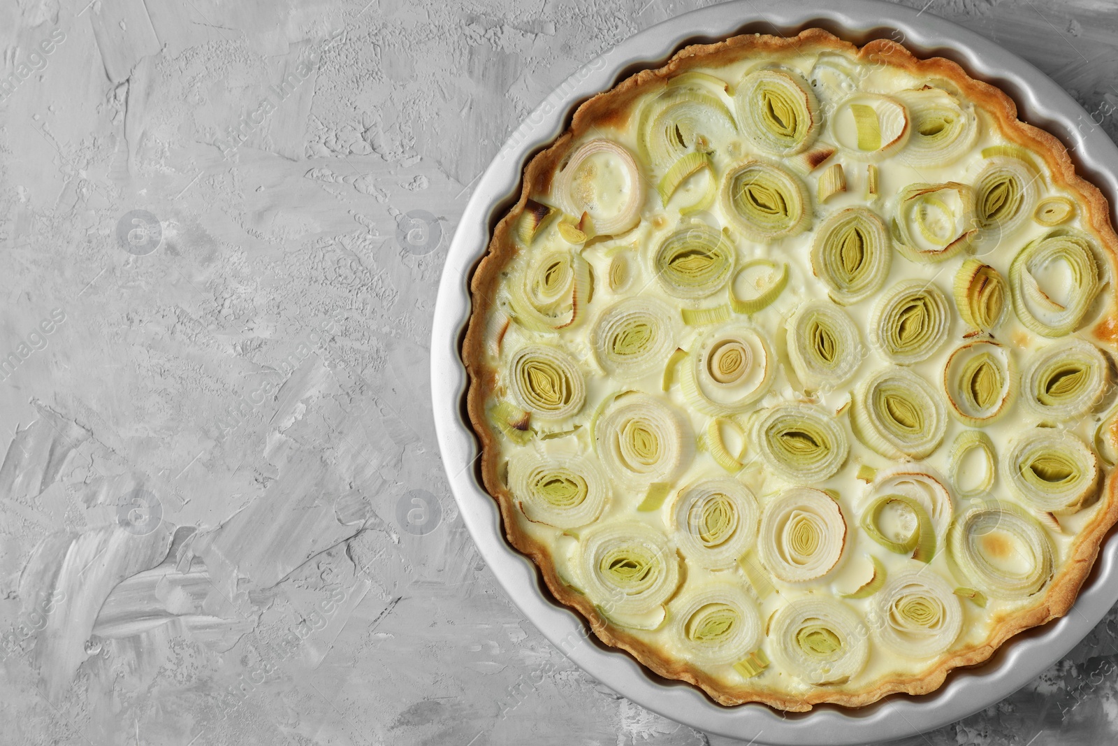 Photo of Freshly baked leek pie on grey textured table, top view. Space for text