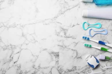 Photo of Flat lay composition with tongue cleaners and teeth care products on marble background. Space for text