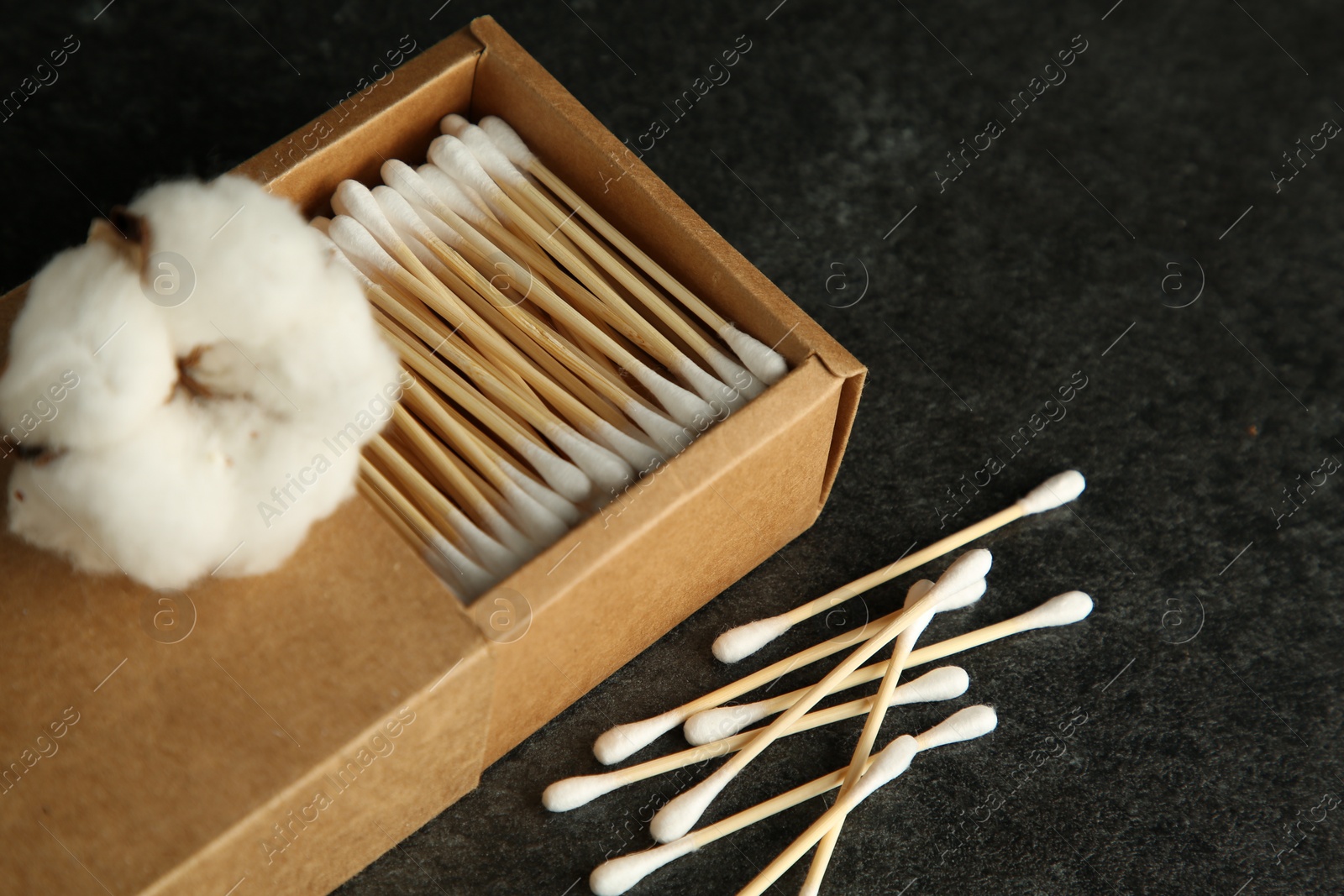 Photo of Cotton swabs and flower on black table, closeup