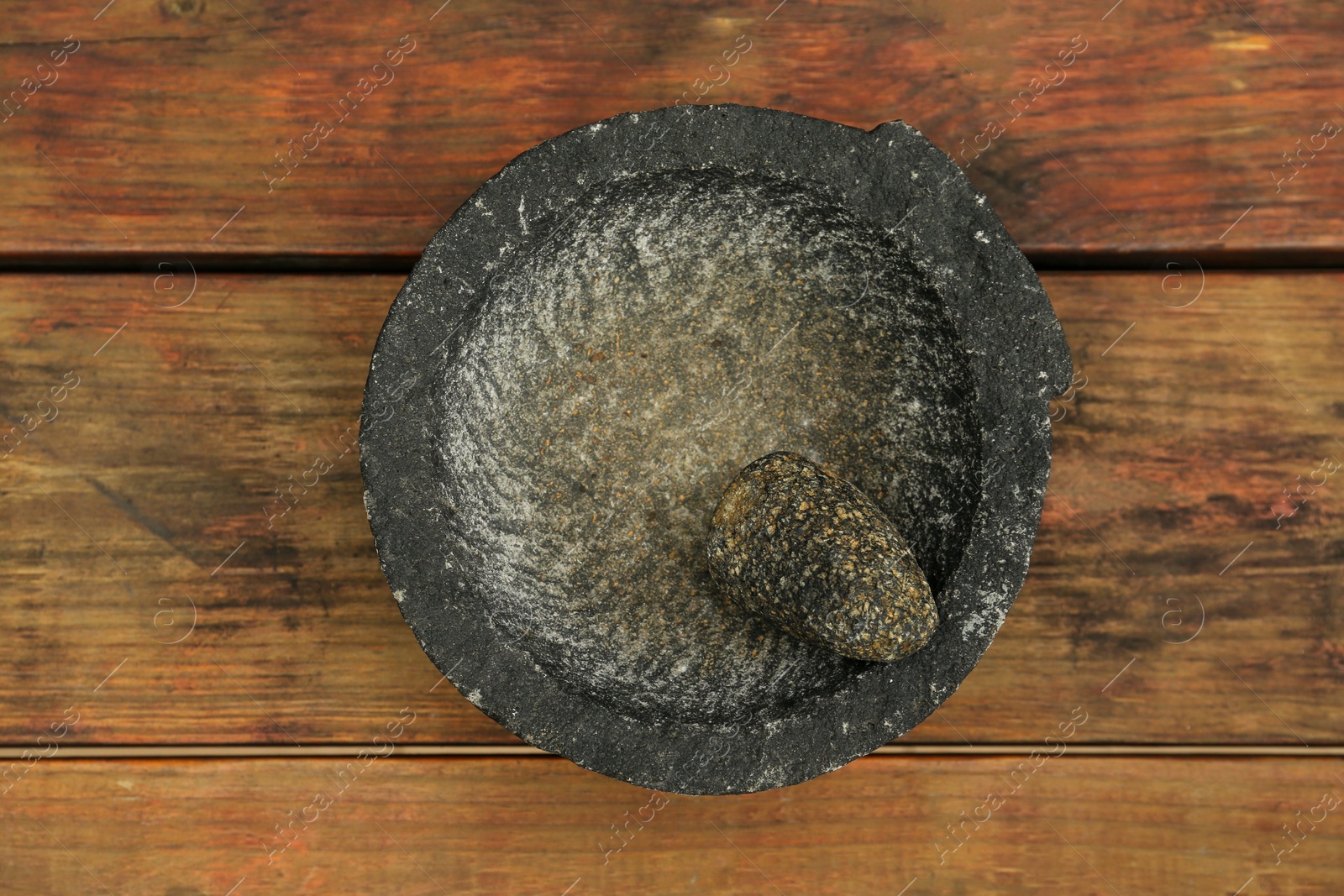 Photo of Empty stone mortar with pestle on wooden table, top view