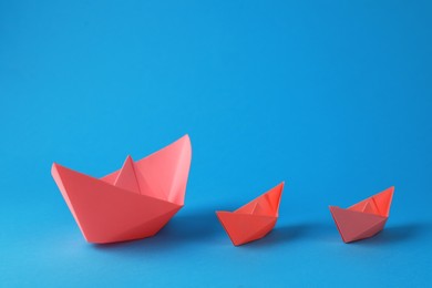 Handmade pink paper boats on light blue background