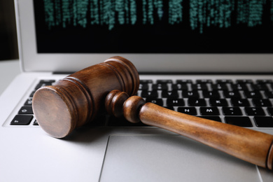 Photo of Modern laptop and wooden gavel on table, closeup. Cyber crime