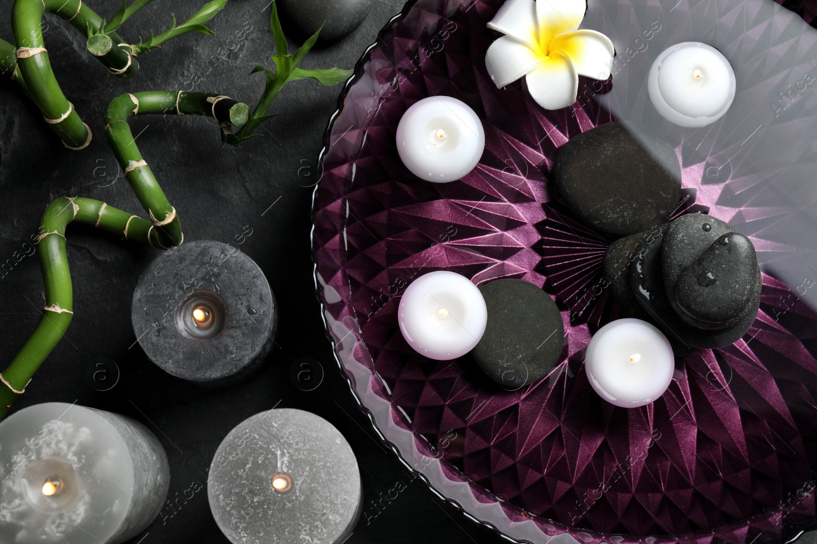 Photo of Flat lay composition with burning candles and spa stones on black table