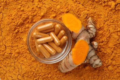 Photo of Pills and raw root on aromatic turmeric powder, flat lay