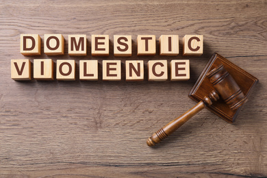 Image of Wooden cubes with words DOMESTIC VIOLENCE and gavel on table, flat lay