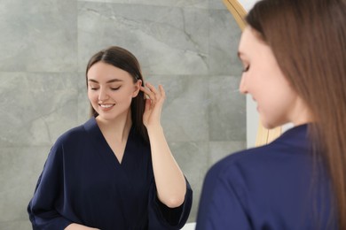 Photo of Beautiful woman in blue robe near mirror indoors