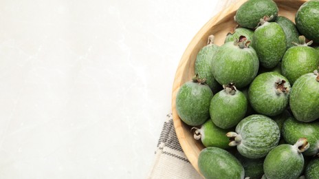 Fresh green feijoa fruits in bowl on light table, top view with space for text. Banner design