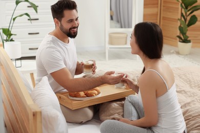 Happy couple having breakfast on bed at home