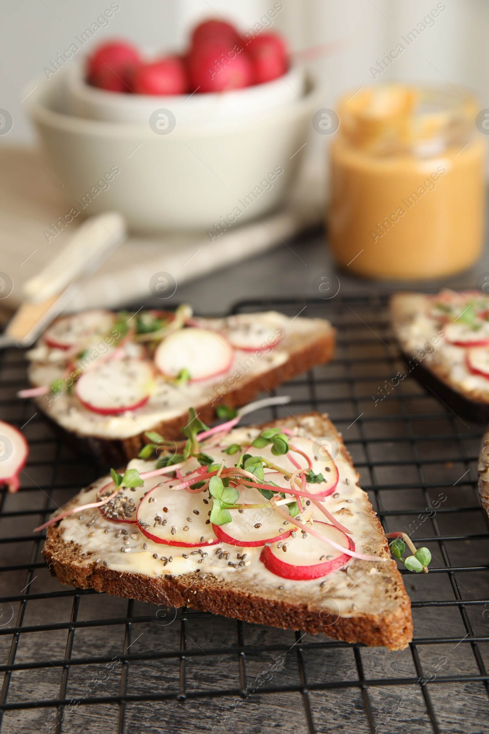 Photo of Tasty toasts with radishes, sprouts and chia seeds on cooling grate