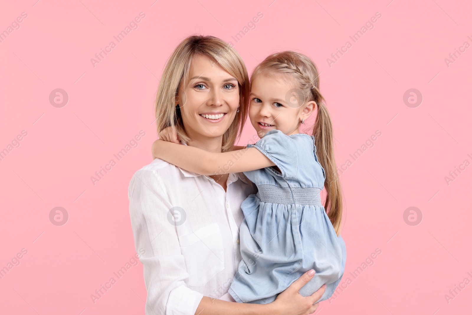 Photo of Daughter hugging her happy mother on pink background