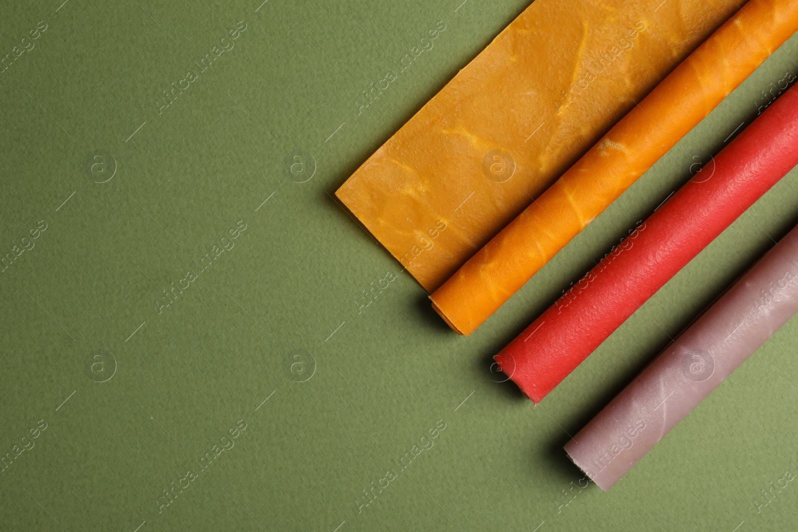 Photo of Colorful beeswax food wraps on green background, flat lay. Space for text