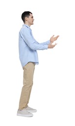 Young man in light blue shirt and beige pants on white background