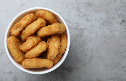 Photo of Bucket with tasty chicken nuggets on grey table, top view. Space for text
