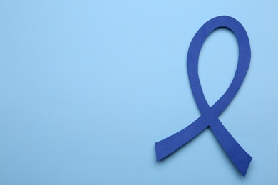 Photo of Blue awareness ribbon on color background, top view with space for text. Symbol of social and medical issues