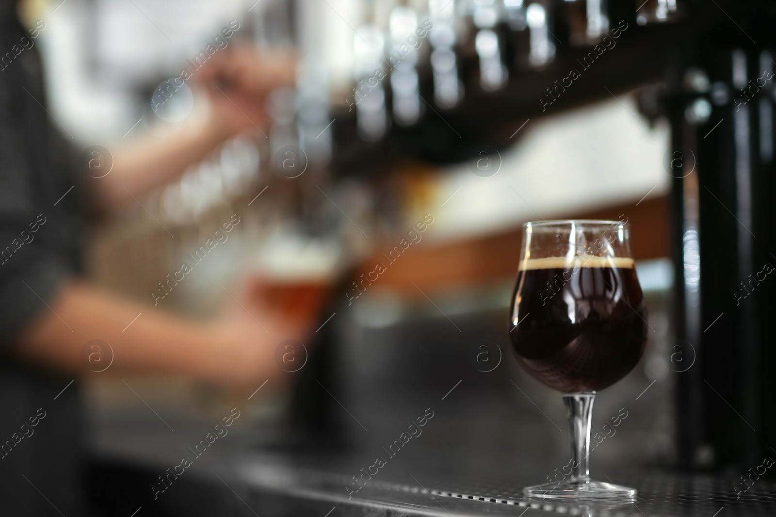 Photo of Glass of cold tasty dark beer on bar counter, space for text