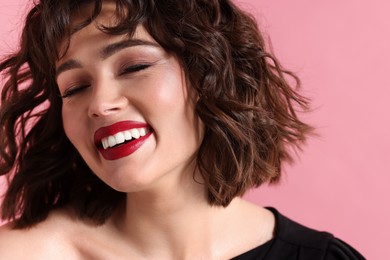 Beautiful young woman with wavy hairstyle on pink background