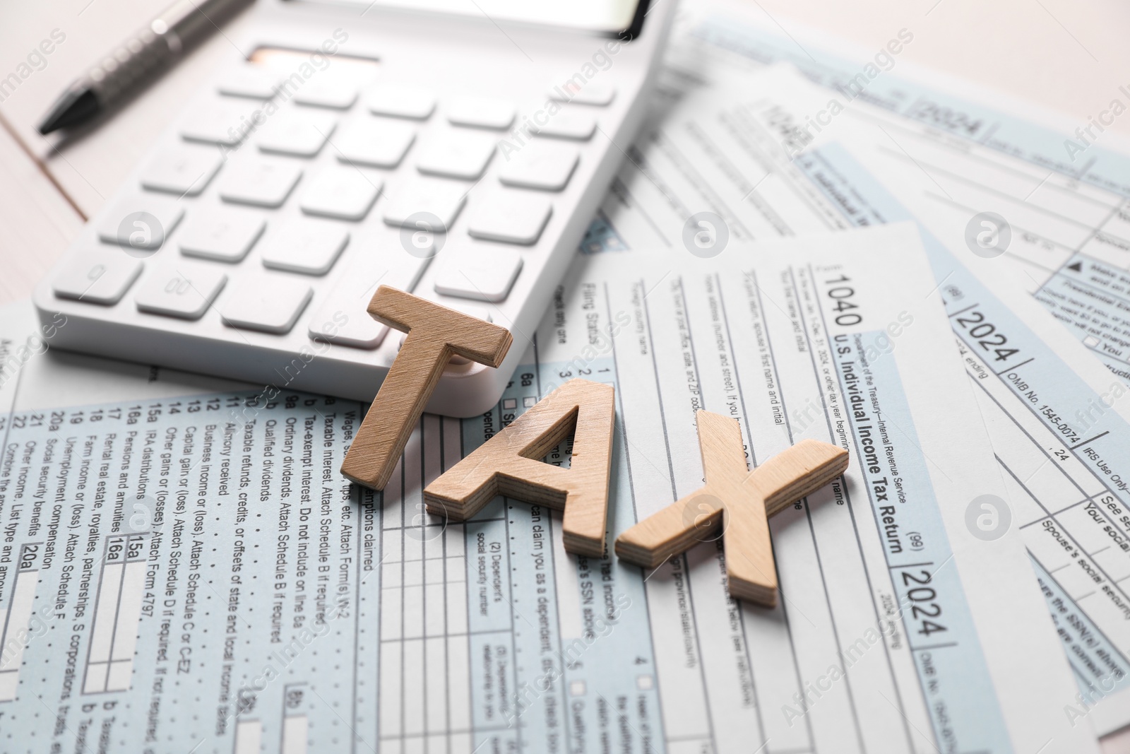 Photo of Word Tax made with wooden letters, calculator and documents on table, closeup