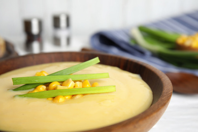 Photo of Delicious corn cream soup in wooden bowl, closeup