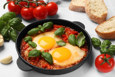 Photo of Delicious Shakshuka served on white tiled table, closeup