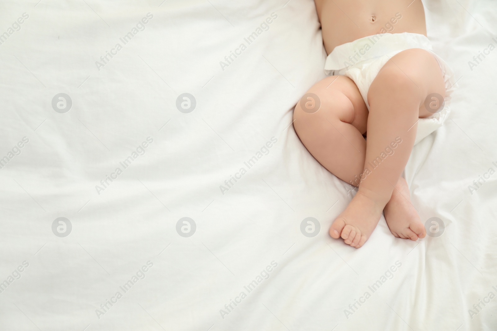 Photo of Cute little baby in diaper on bed, top view. Space for text