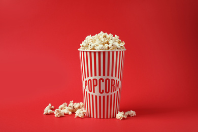 Photo of Delicious popcorn in paper cup on red background