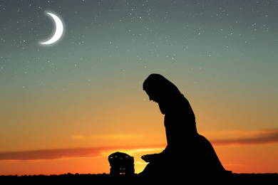 Silhouette of Muslim woman praying outdoors. Holy month of Ramadan