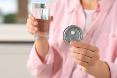 Woman holding blister of emergency contraception pill, closeup