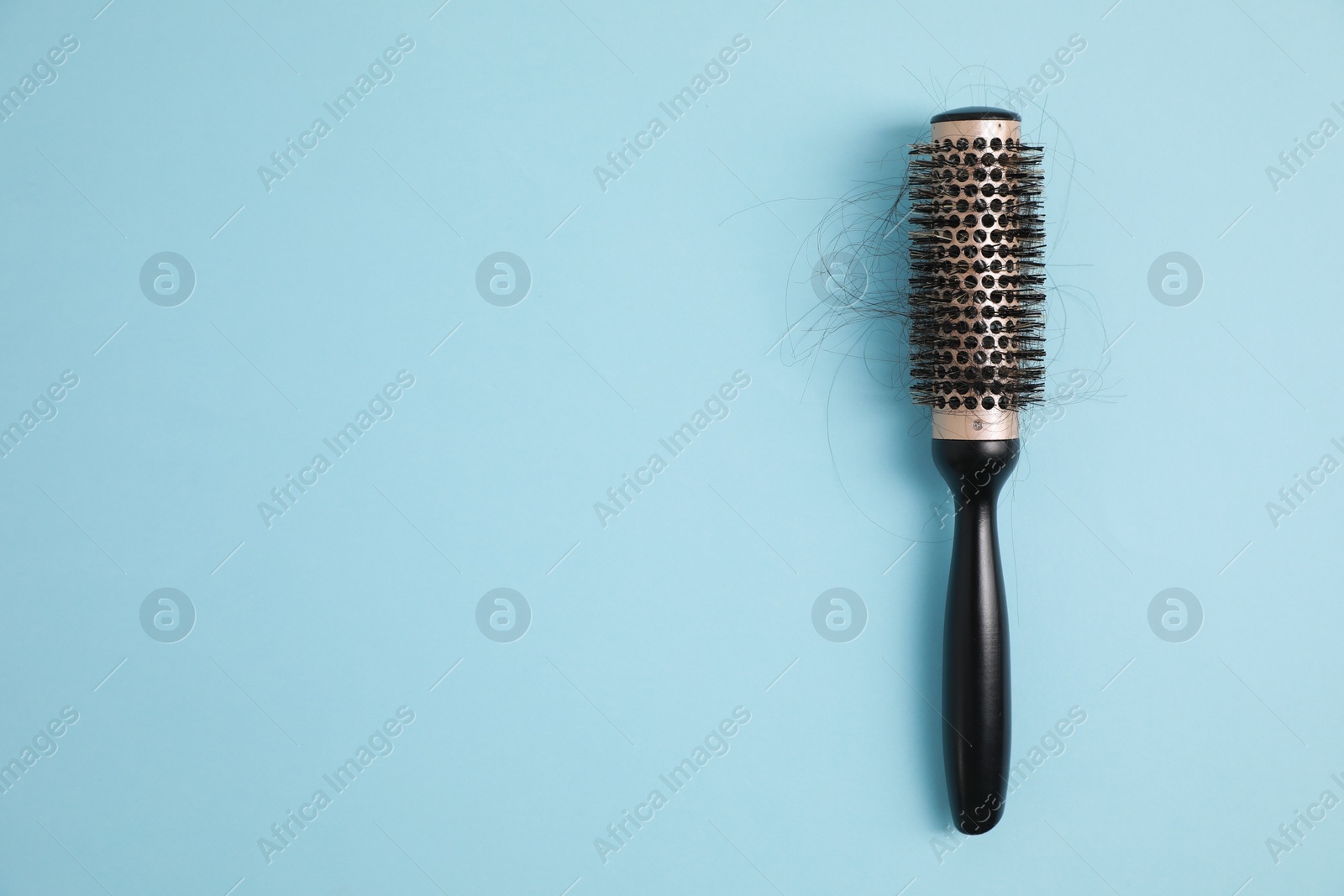 Photo of Professional brush with lost hair on light blue background, top view. Space for text