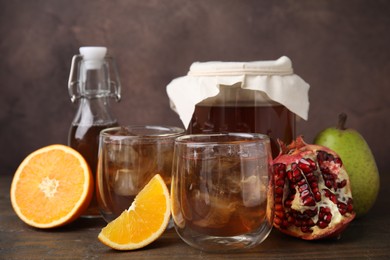 Photo of Tasty kombucha with ice cubes and fruits on wooden table