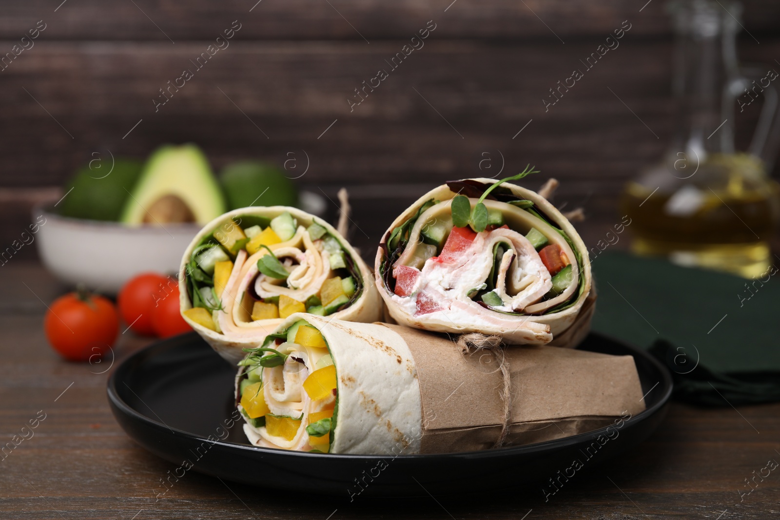 Photo of Delicious sandwich wraps with fresh vegetables on wooden table