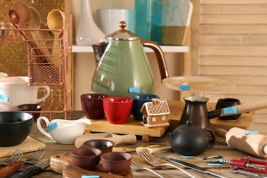 Many different cooking utensils on wooden table indoors. Garage sale