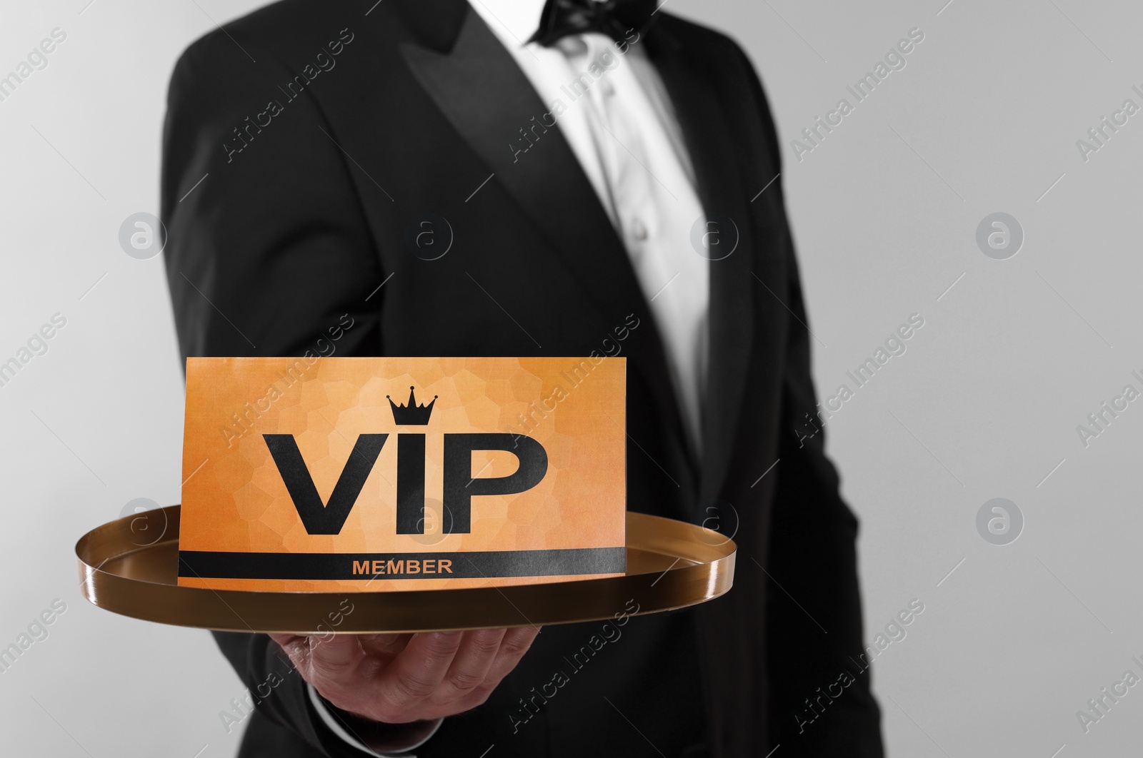 Photo of Man holding tray with VIP sign on light grey background, closeup. Space for text