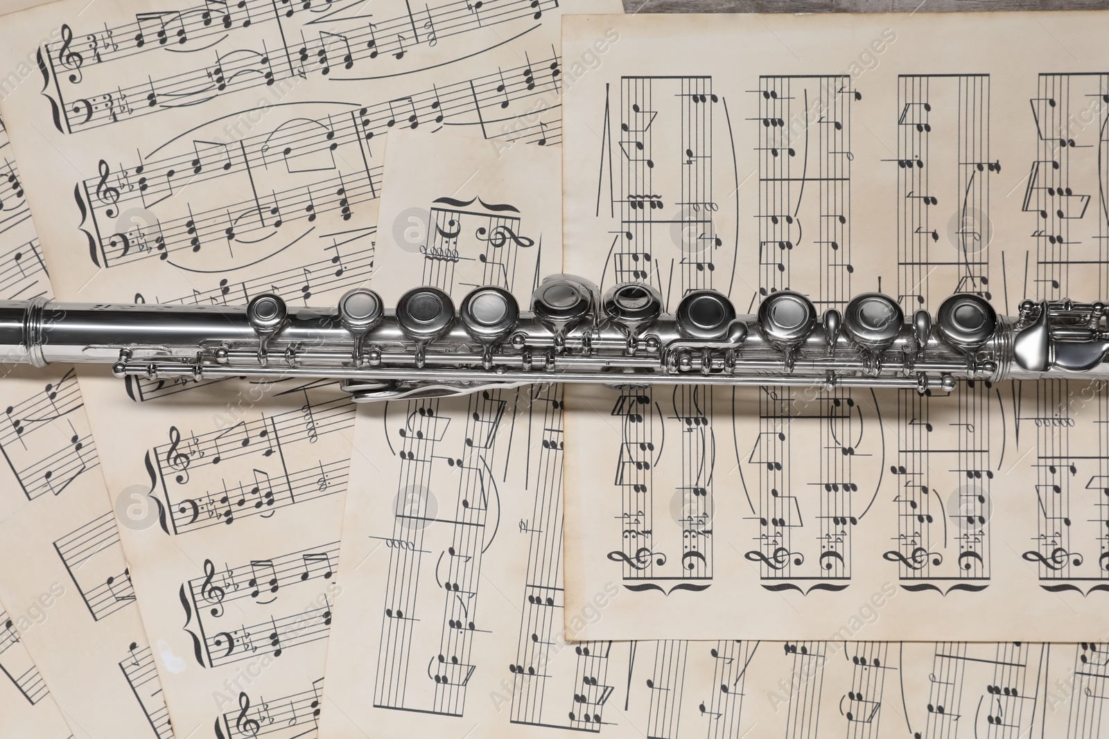 Photo of Classical flute on sheets with musical notes, top view