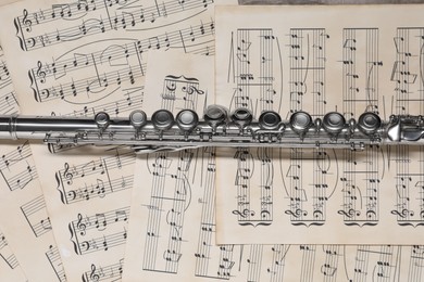 Photo of Classical flute on sheets with musical notes, top view