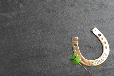 Photo of Clover leaf and horseshoe on grey stone table, flat lay with space for text. St. Patrick's Day celebration