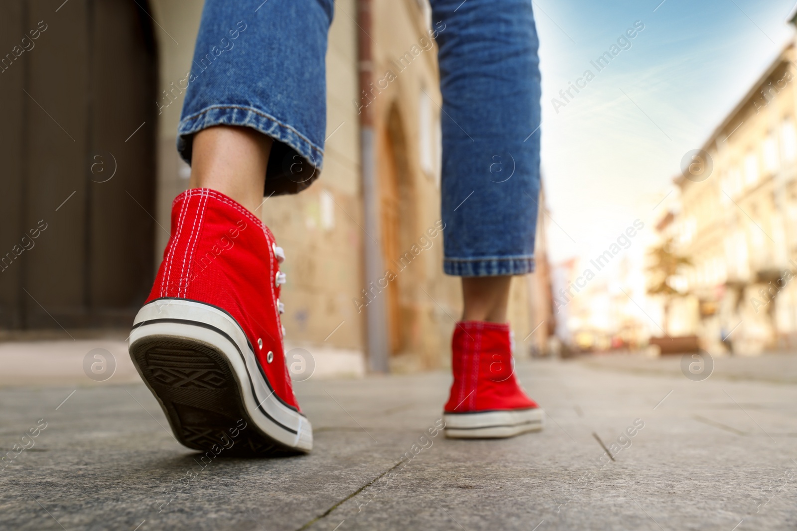 Photo of Woman in stylish sneakers walking on city street, closeup