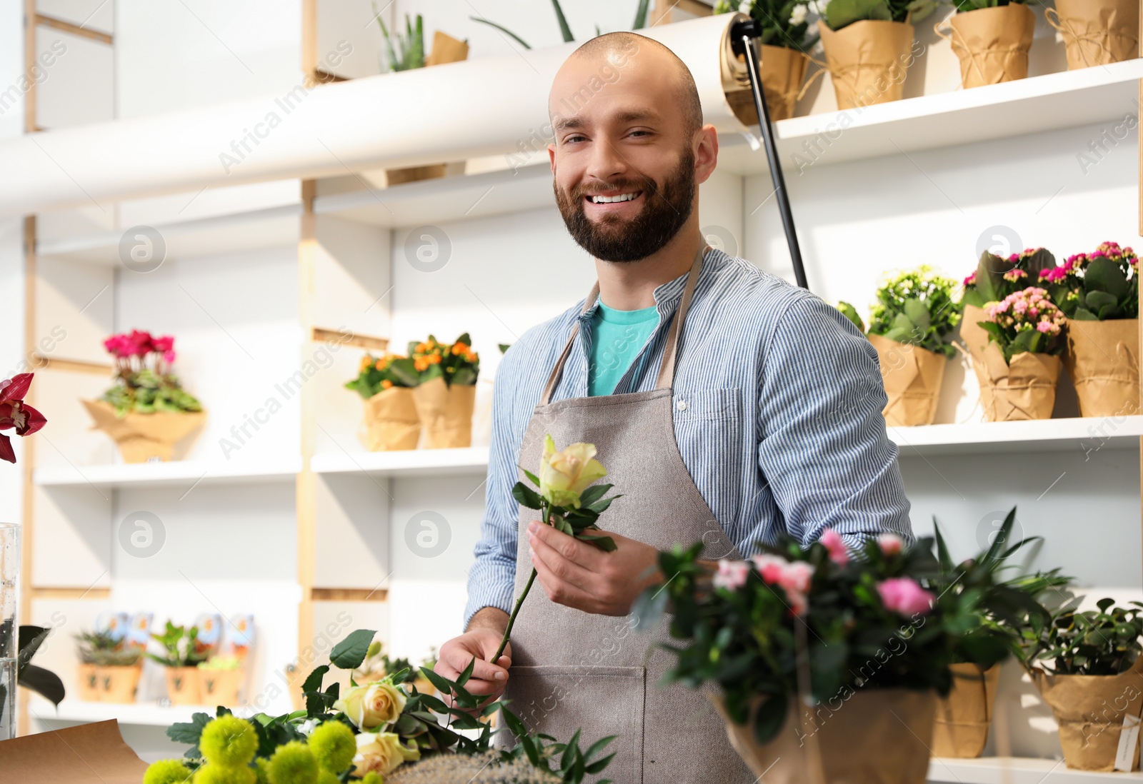 Photo of Florist making bouquet with fresh flowers at table in shop