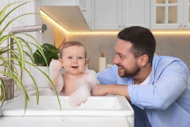 Photo of Father washing his little baby in sink at home