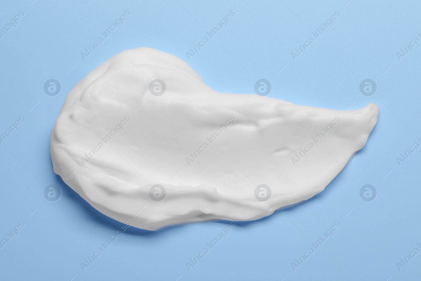 Photo of Sample of shaving foam on light blue background, top view