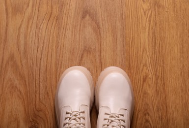 Pair of stylish beige leather shoes on wooden floor, top view. Space for text