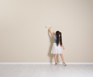 Photo of Child painting color wall with roller brush. Space for text