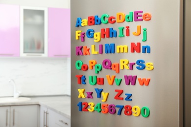 Photo of Refrigerator door with colorful magnetic letters and numbers in kitchen. Space for text