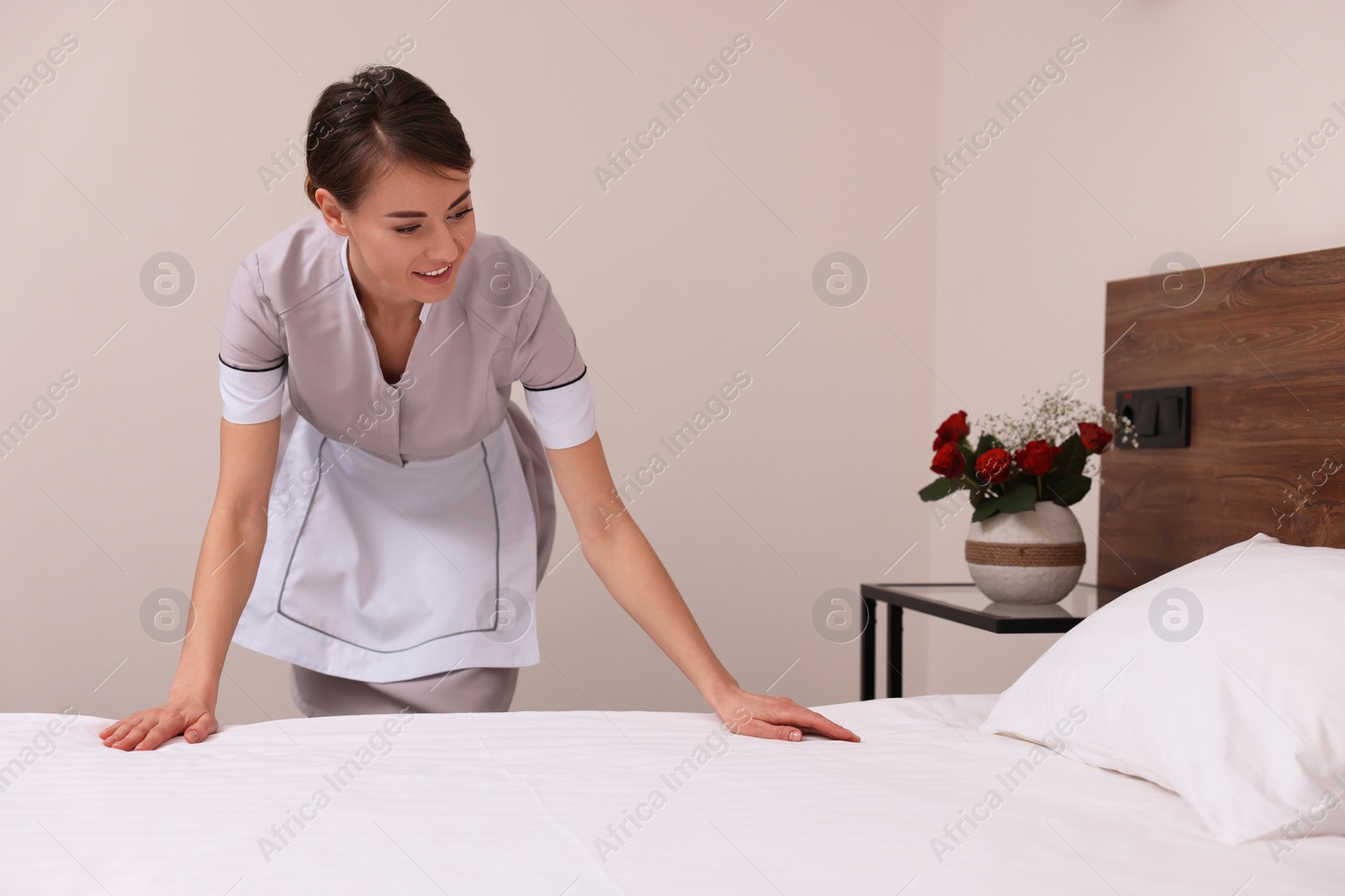 Photo of Beautiful chambermaid making bed in hotel room