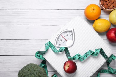 Photo of Scales, measuring tape, fresh fruits and almonds on white wooden table, flat lay with space for text. Low glycemic index diet
