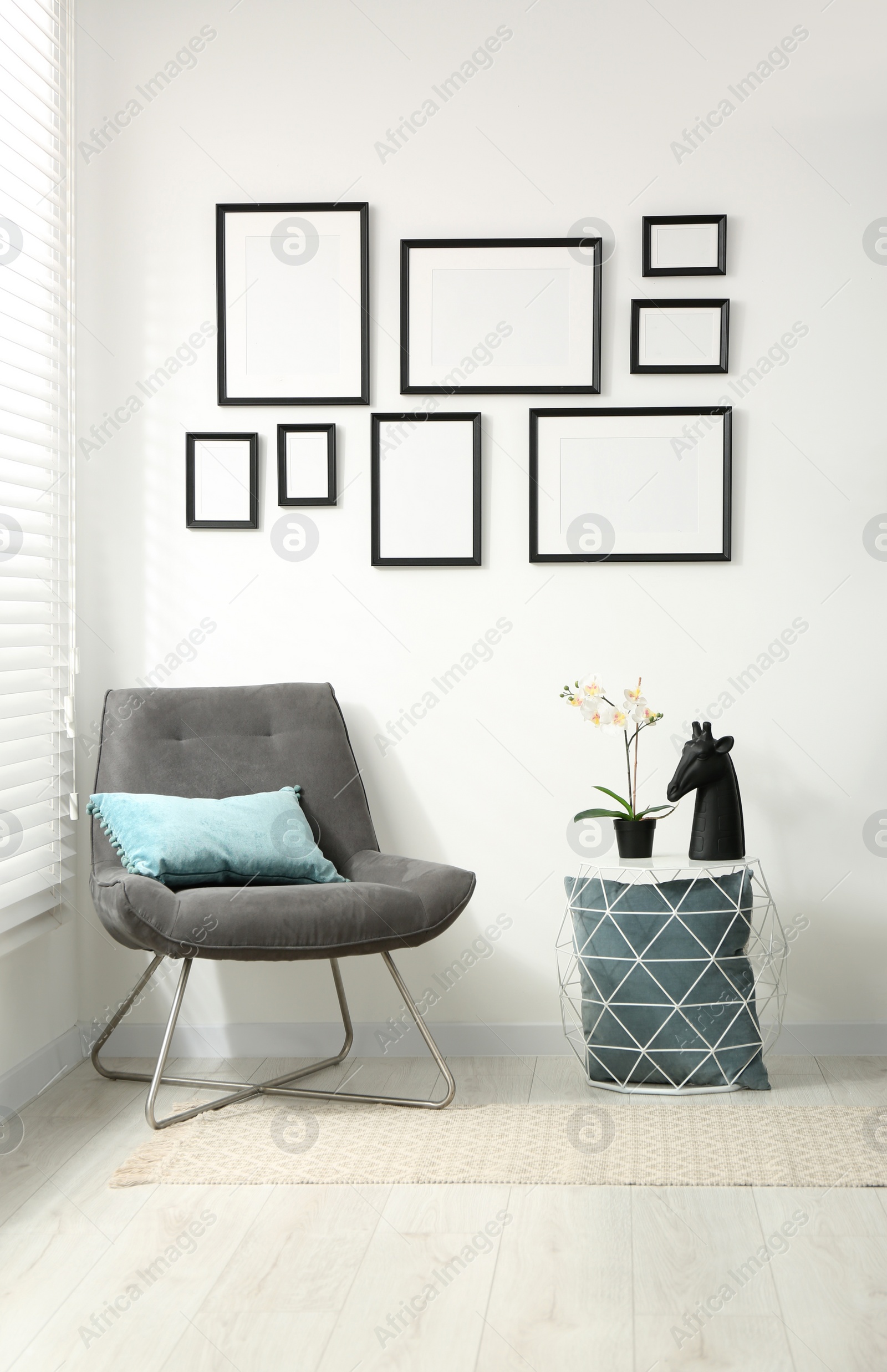 Photo of Stylish room interior with empty frames hanging on white wall and comfortable furniture