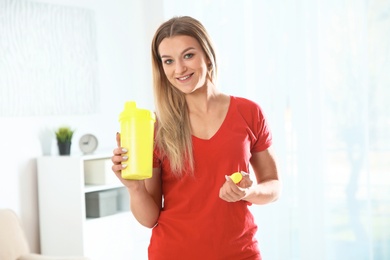 Photo of Young woman with bottle of protein shake at home