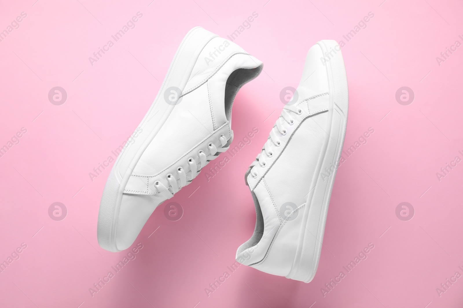 Photo of Pair of stylish white sneakers on pink background, top view